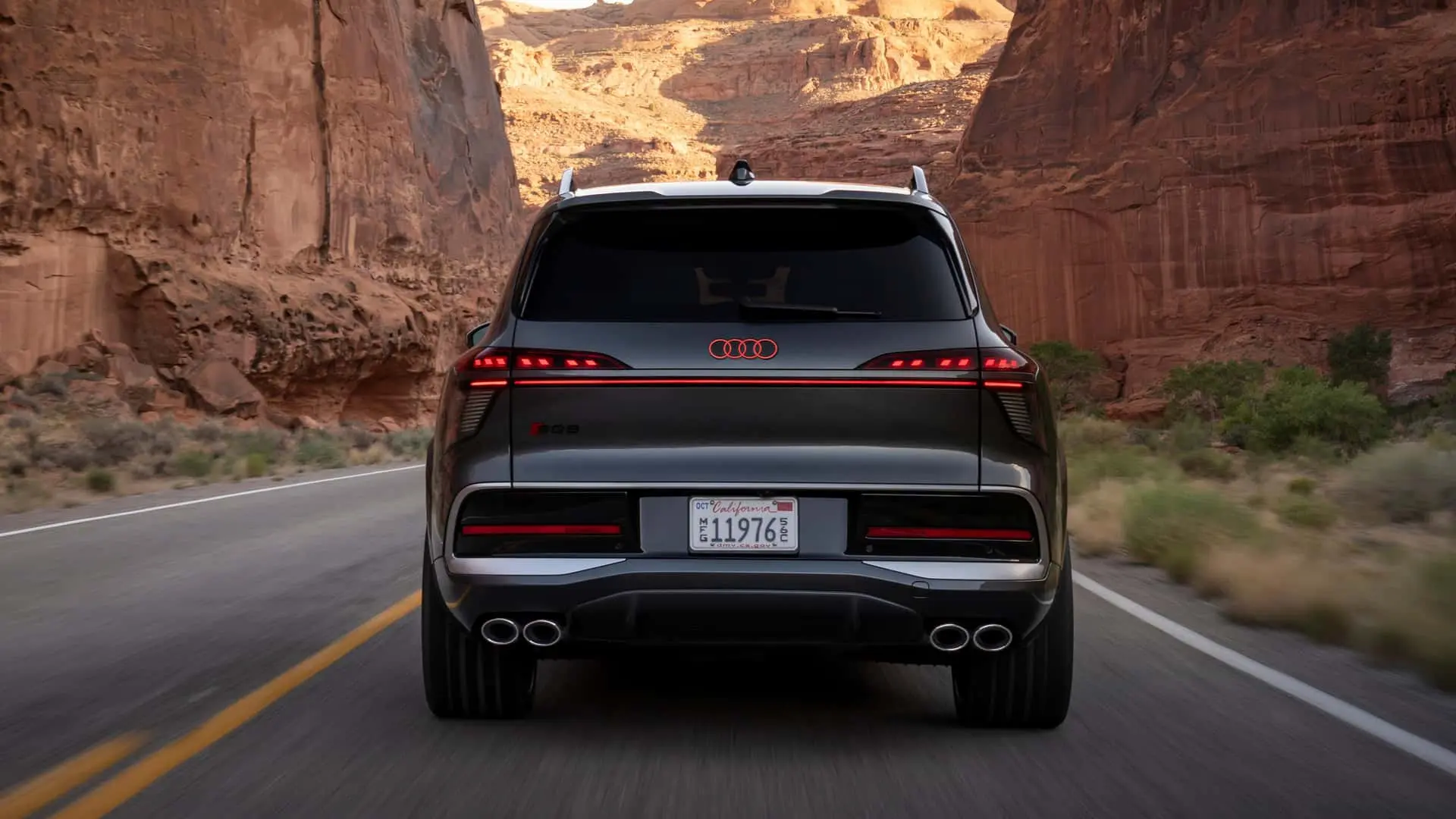 نمای عقب خودروی شاسی‌بلند آئودی (Audi) در جاده‌ای میان دره‌های سنگی